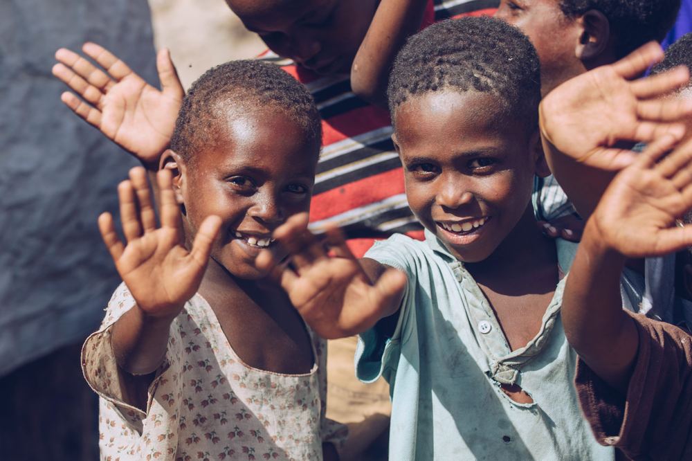 Children laugh and wave at the camera
