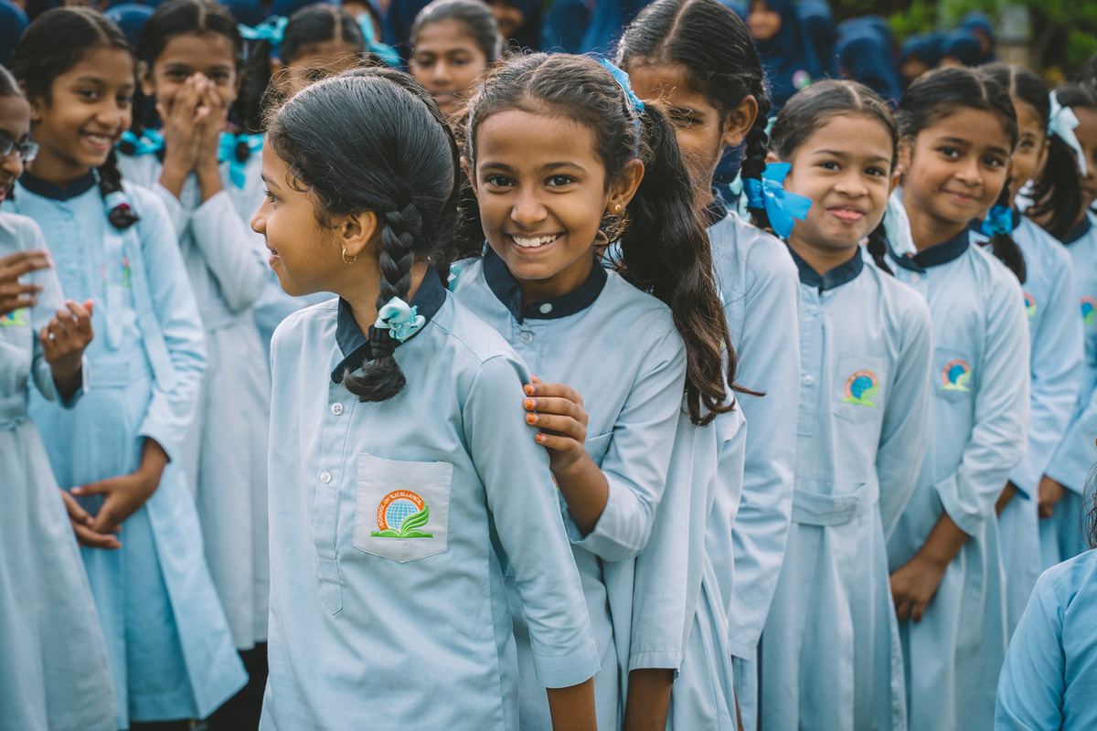 Schoolgirls in uniform smile as they line up