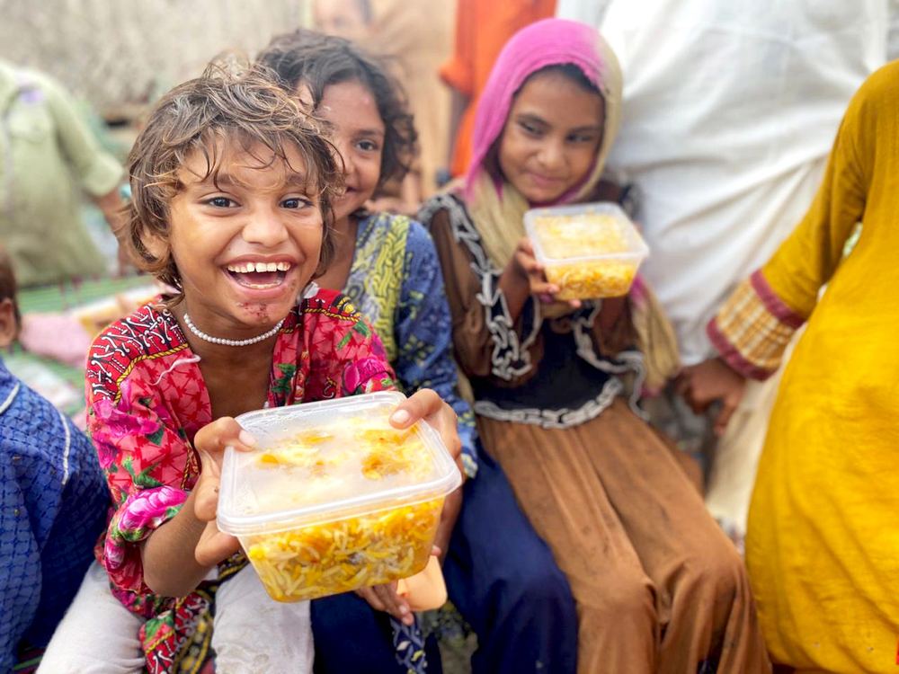 Girls hold up boxes of food and smile