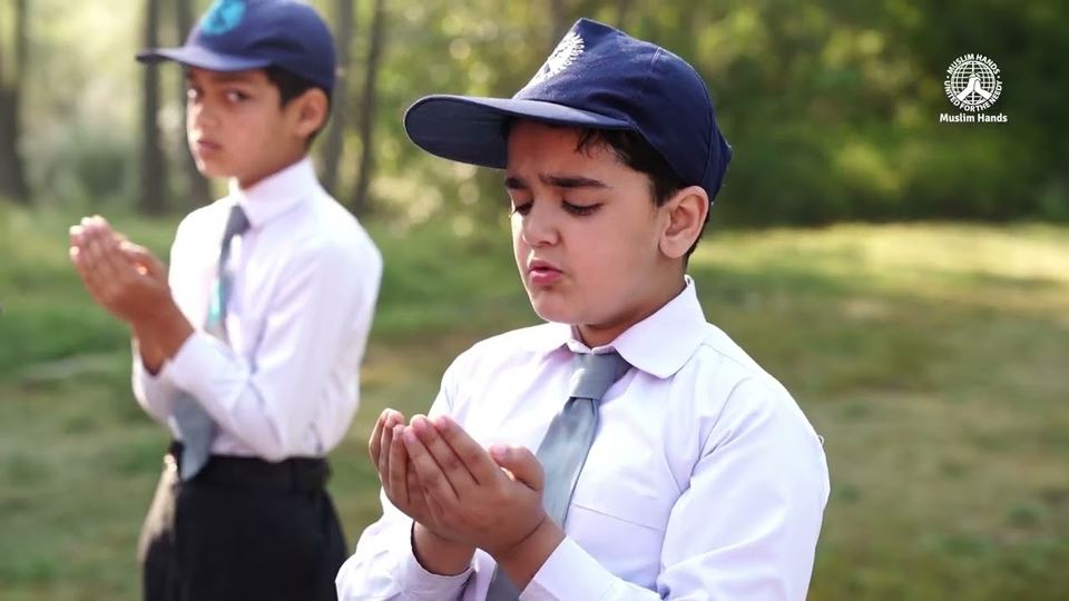 Two schoolboys raise their hands in prayer