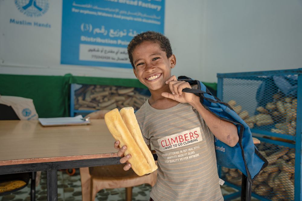 A boy smiles as he receives bread