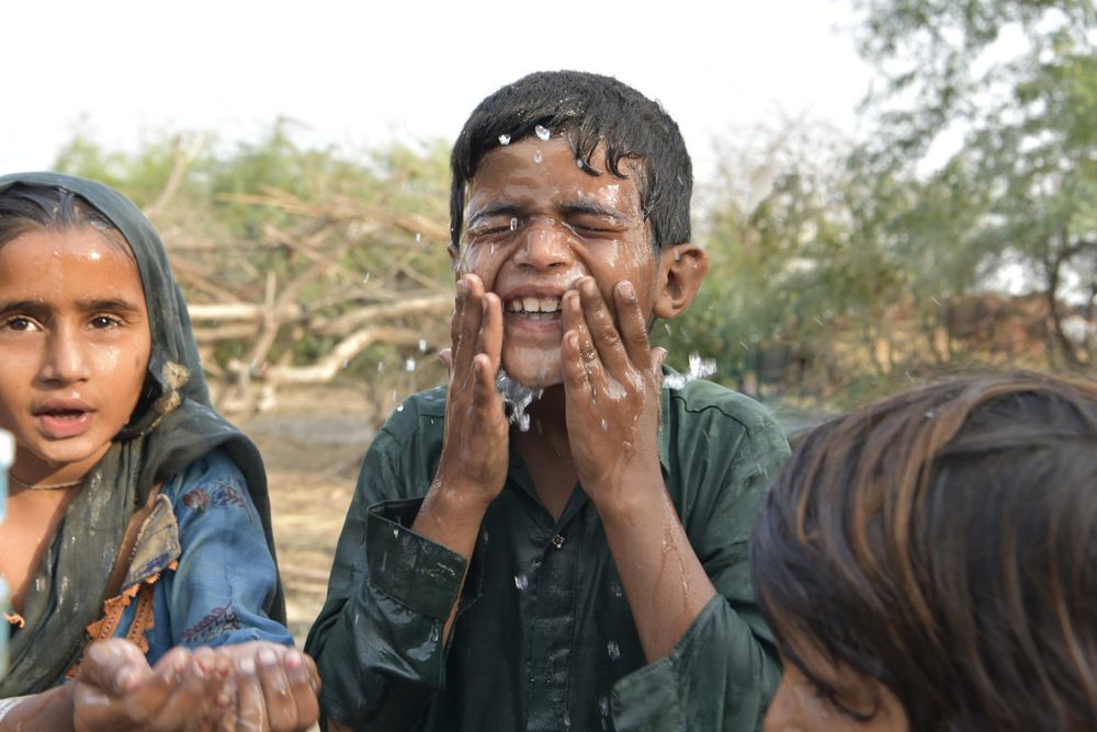 A boy splashes clean water on his face