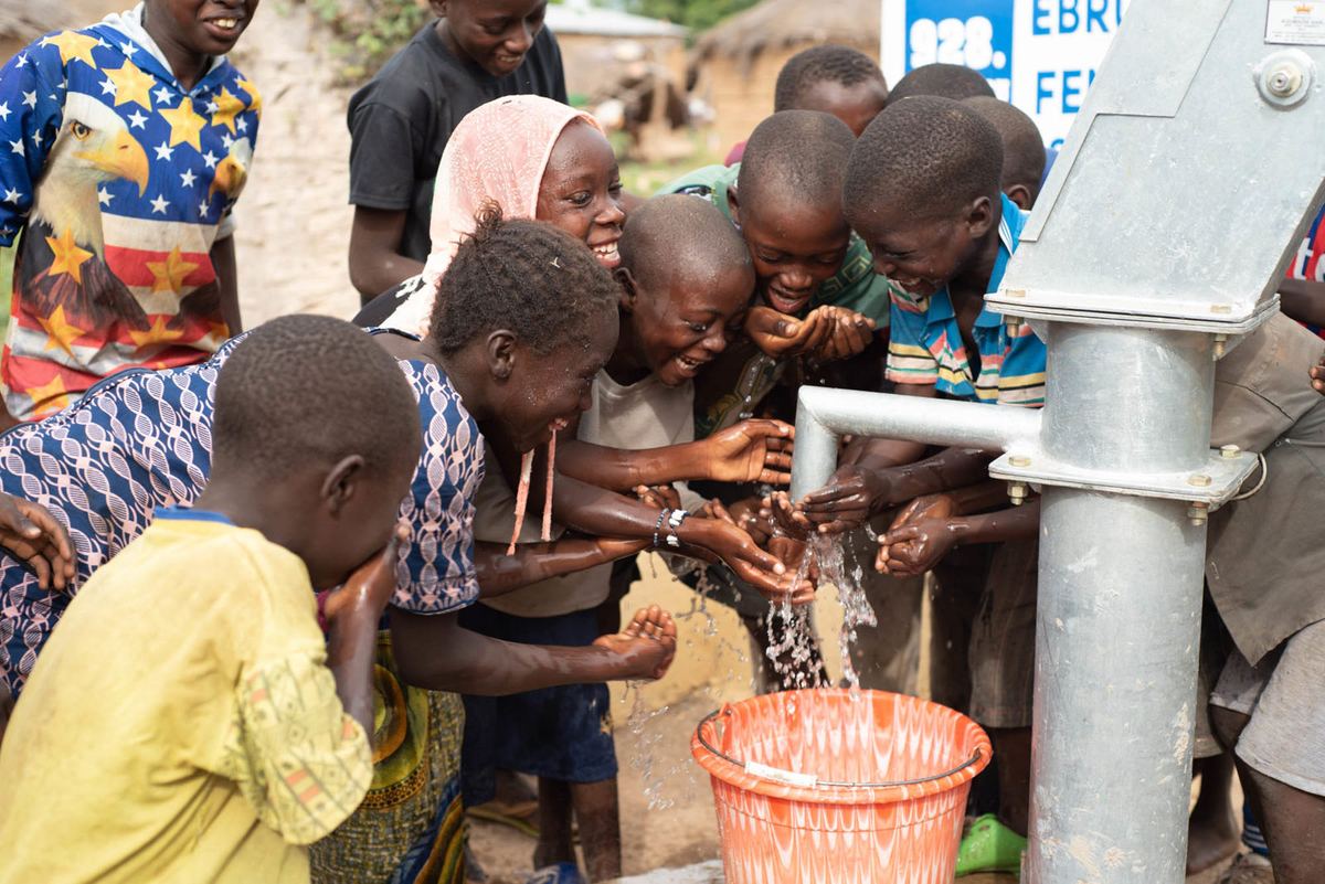 Children crowd around a new hand pump to wash