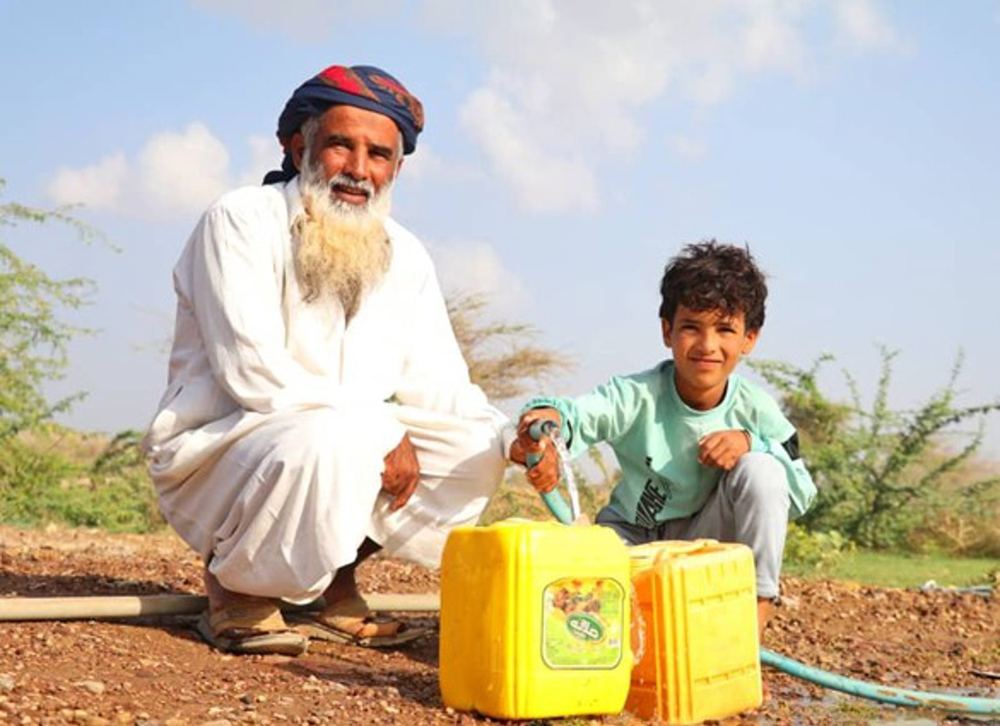 Jamal and his son fill yellow containers with clean water
