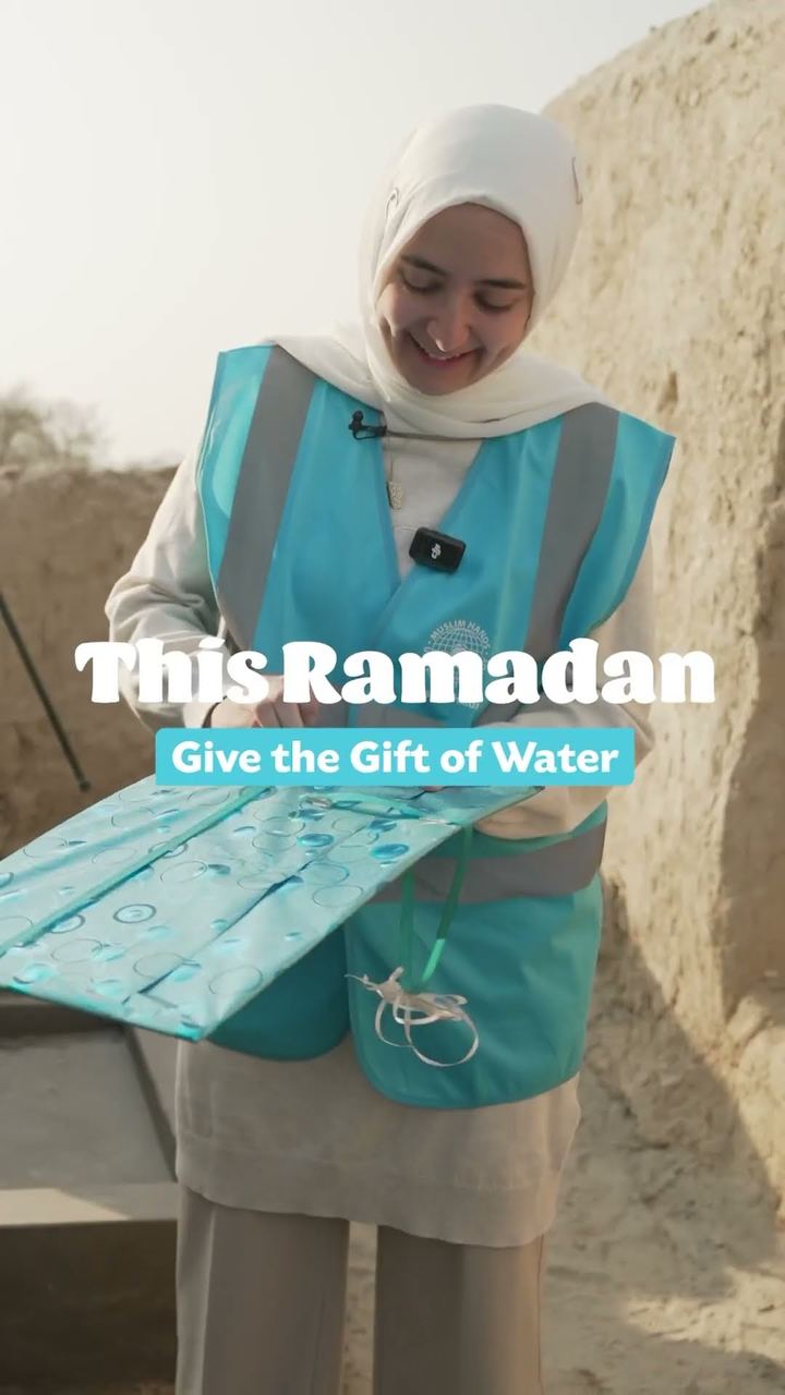 A Muslim Hands volunteer holds up a Tube Well sign